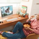 Person enjoying chips while watching skateboarding on a computer at a cozy desk