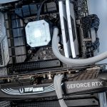 Close-up of a gaming PC build featuring a GeForce RTX graphics card, illuminated hardware, and liquid cooling setup