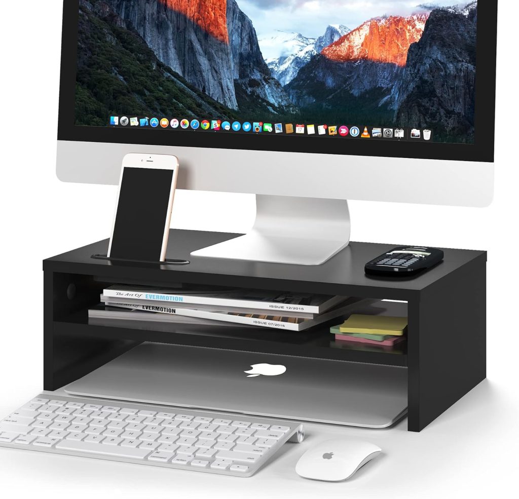 Desktop computer on black stand with smartphone, calculator, books, and keyboard in an organised setup