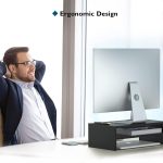 Man relaxing at desk with ergonomic monitor setup in bright office